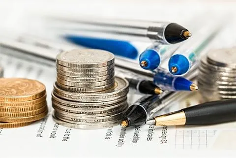 Finanzierung Physiotherapie eröffnen - Existenzgründer Finanzierungs-Service - Geldmünzen auf einem Dokument - Finanzierung bei Secona